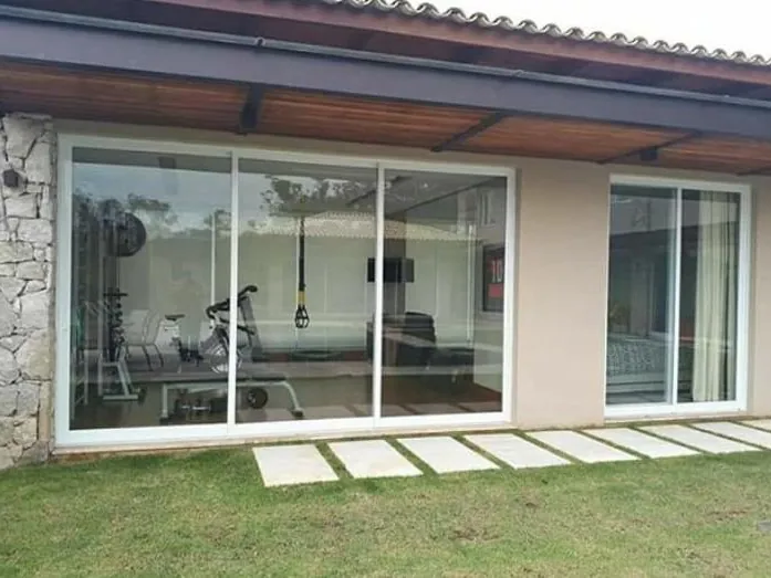 Academia envidraçada com parede de pedra e caminho no jardim