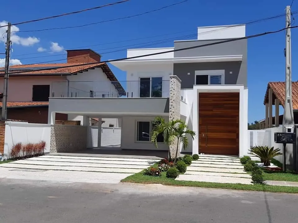 Fachada de sobrado branco com porta alta de madeira e escada de acesso