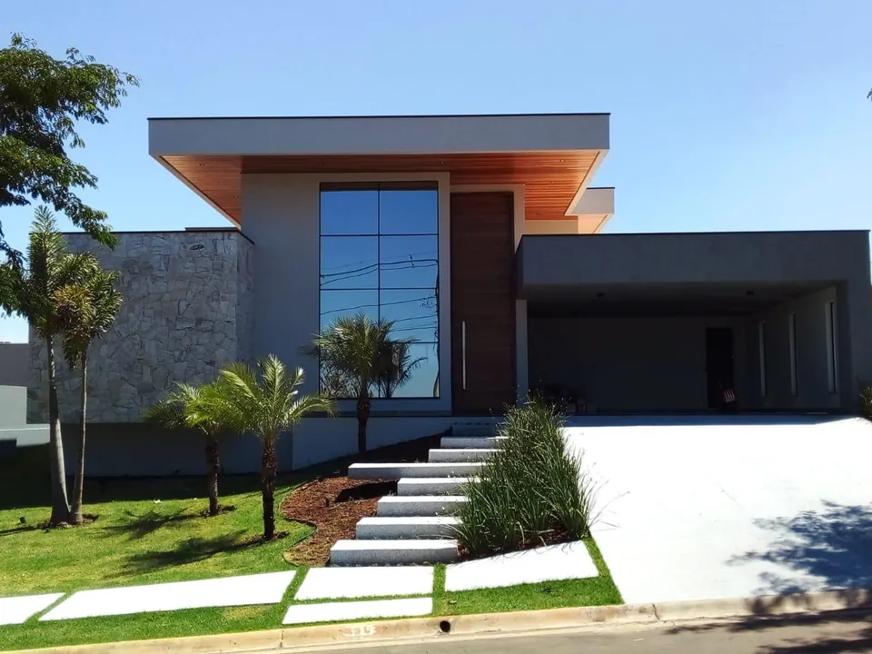 Fachada de residência térrea em pedra e madeira com escada e jardim